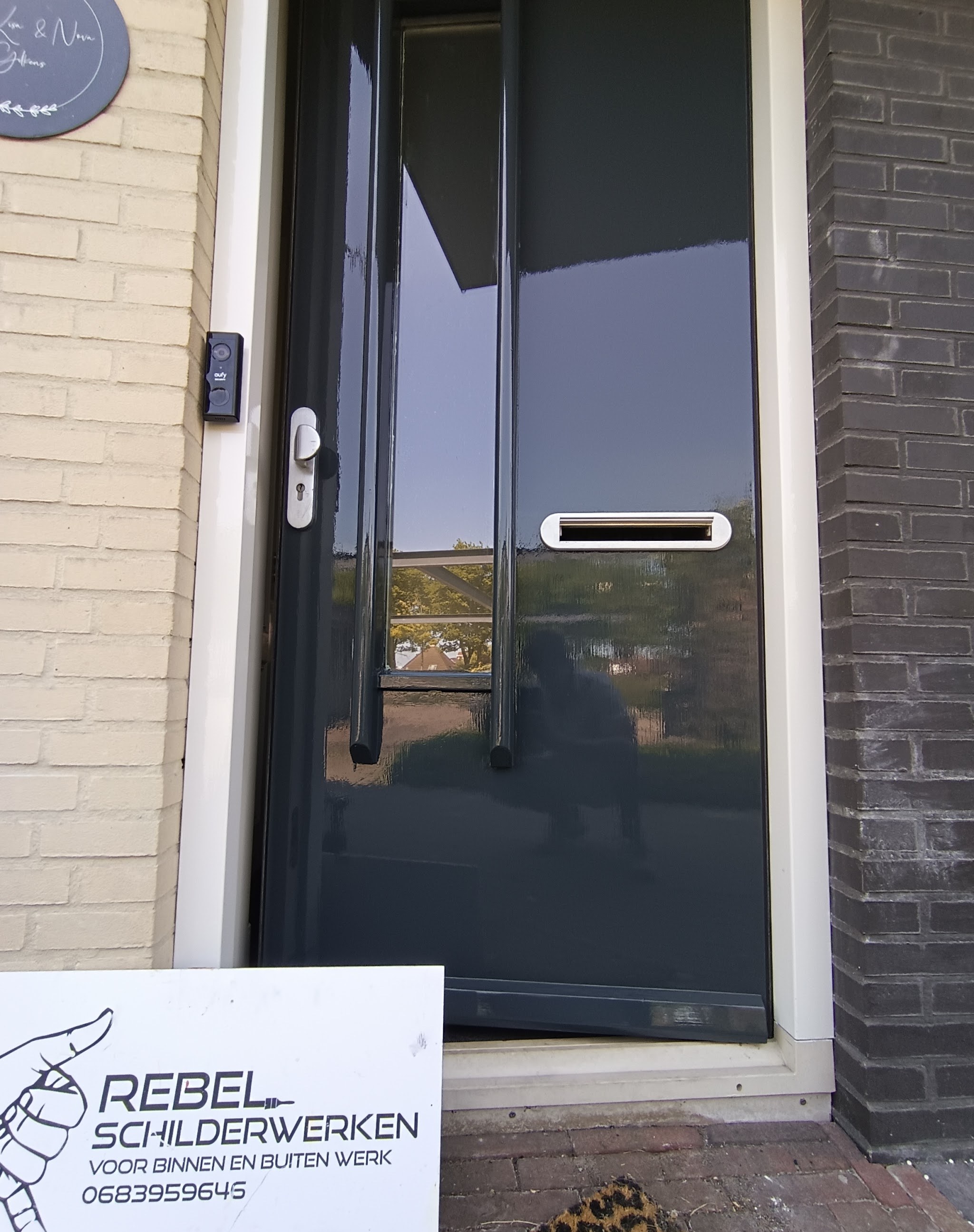 Antraciet geschilderde voordeur en kozijn met het bord van Rebel Schilderwerken