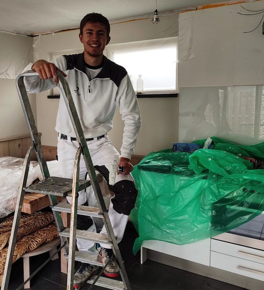 Rick Rebel in witte schildersbroek bij een trapje, tijdens een klus binnen